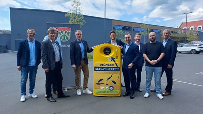 Die gelben Sammelcontainer stehen (hier: Standort REWE-Parkplatz in der Frankfurter Straße). V.l.: Jürgen Pfeifer (Fachdienst Steuern, Abfallwirtschaft), Erster Stadtrat Uwe Michael Hajdu, Ehrenamtlicher Stadtrat Ulf Köper, Bürgermeister Steffen Ball, Johann Trojan (Business Development, Münzer), Ewald-Marco Münzer (Miteigentümer Münzer Bioindustrie und Geschäftsführer Münzer Deutschland) , Johannes Kallien (Münzer Deutschland), Sedat Tekin (REWE), Albert Bechtold (Münzer Deutschland). 