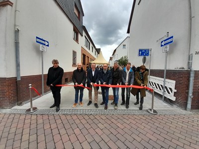 Die Umgestaltungsmaßnahme ist abgeschlossen, und die Bürgermeister-Kämmerer-Straße ist offiziell „wiedereröffnet“. V.l.: Erster Stadtrat Uwe Michael Hajdu, Stadtverordnetenvorsteher Peter Jakoby, Bürgermeister Steffen Ball, Fachdienstleiter Tiefbau Thomas Möller, zwei Vertreter der durchführenden Baufirmen, Yvonne Woll von der ProjektStadt Eine Marke der Unternehmensgruppe Nassauische Heimstätte | Wohnstadt (Foto: R. Dinkelborg/Magistrat)