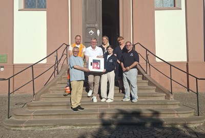 Bei der Übergabe des neuen Defibrillators in St. Cäcilia. V.l. erste Reihe: Pfarrer Martin Weber, Bürgermeister Steffen Ball, Greta Mereu und Sebastian Bergold (Voraushelfer-System/Team ERD), v.l. hintere Reihe: Nikolas Lütz (Bauhof-Team), Ninja Weis (Ambulante Intensivschwester) und Beate Schütz (Projektmanagement) der Asklepios Klinik Langen.