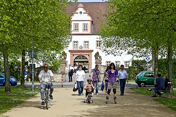 Schlossallee mit Radfahrenden und Fußgänger*innen.